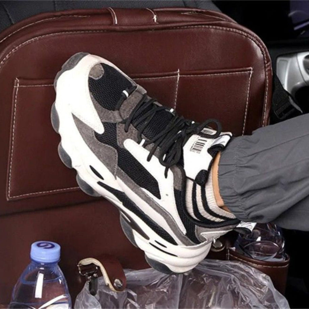 Person's shoe kicking brown seat-back organizer, showing durable easy-clean PU leather surface