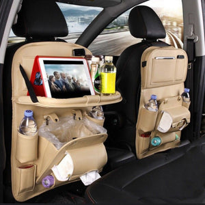 Beige seat-back organizer with folding tray, bottles and trash pocket against dark car interior