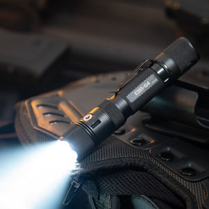 Powertac E9R G4 tactical flashlight on gear, powerful white beam shining across a backpack