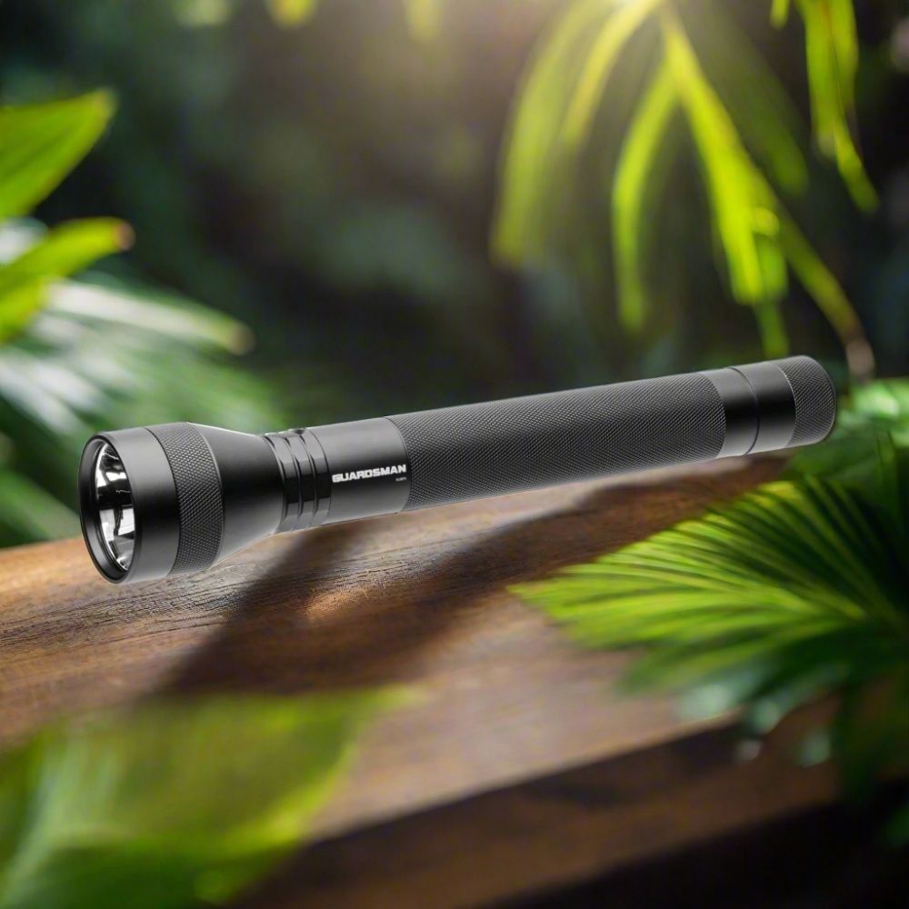 Powertac Guardsman rechargeable patrol flashlight on wooden table with green tropical foliage