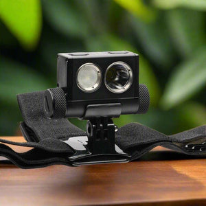 Powertac Explorer HL-10 tactical headlamp on elastic strap resting on a wood table with green foliage background