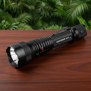 Powertac Huntsman XLT long range tactical flashlight on wood table with lush green jungle background