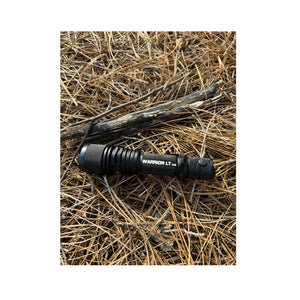 Powertac Warrior LT G5 tactical flashlight lying on dry pine needles in the woods.