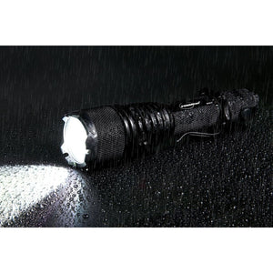 Powertac Warrior LT G5 flashlight shining in heavy rain on a wet dark surface, demonstrating waterproof performance.