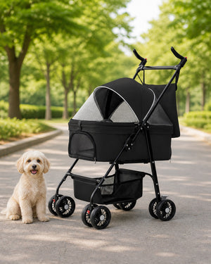 Black four-wheel pet stroller beside a small cream-colored dog on a tree-lined park path.