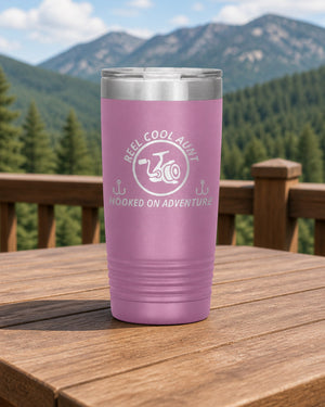 Light Purple 20-ounce REEL COOL AUNT engraved tumbler on a sturdy cabin porch table overlooking forested mountains.
