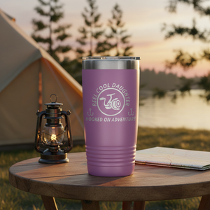 REEL COOL DAUGHTER light purple 20oz tumbler on a warm campsite side table at sunset.