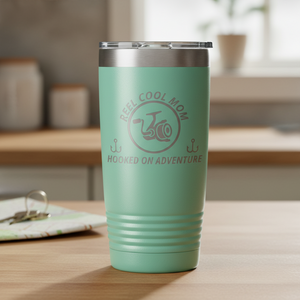 REEL COOL MOM teal 20oz tumbler on a warmly lit everyday counter.